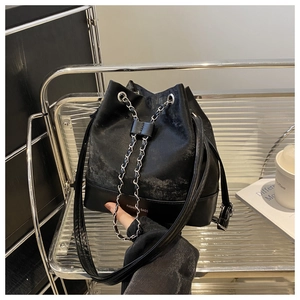 Detailed macro view of the black mixed-texture bucket bag with chain drawstring and strap