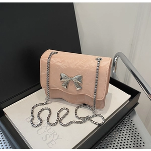 Close-up of pink crossbody bag with pleated texture and silver bow buckle detail