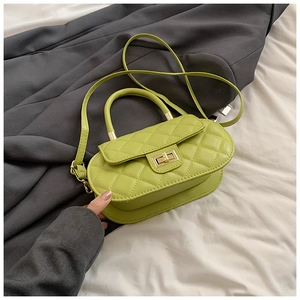 Detail of avocado green quilted handbag with gold clasp on grey coat background
