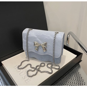 Detail of light blue crossbody bag with marble pattern and silver bow metal clasp