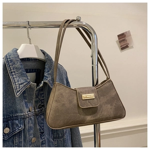 Detail of vintage baguette bag with gold metal plaque paired with denim jacket