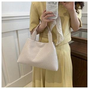 Detail of cream white woven bucket bag showing intricate checkerboard texture and handle