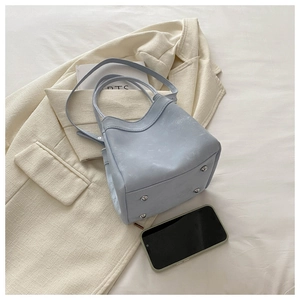 Detailed view of light blue bucket bag with silver feet and textured matte finish