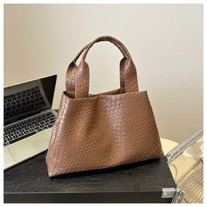 Close-up of the vintage brown crocodile-embossed leather texture and handle on a tote bag
