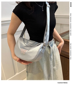 Detail of silver crossbody dumpling bag featuring pink butterfly embroidery and lychee texture