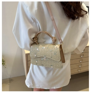 Detail of woven straw handbag featuring delicate floral embroidery and a top handle strap