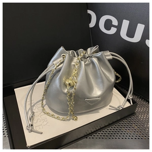 Detail of silver bucket bag showing drawstring closure and golden chain with orb charm