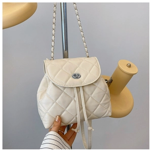 Close-up of cream quilted mini backpack with silver twist lock and metal chain strap