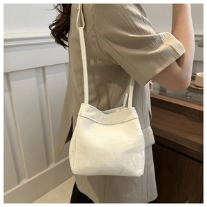 Detailed view of a soft white bucket bag with textured faux leather on a female model