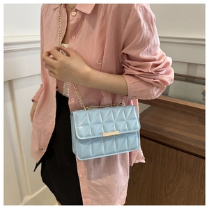 Close-up of light blue quilted leather handbag with gold metal clasp and chain strap