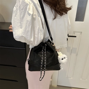 Large black leather bucket bag with silver chain strap and white plush charm on model