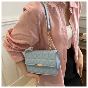 Close-up of light blue quilted shoulder bag featuring gold hardware and chain strap details