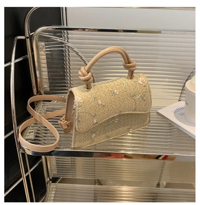 Detailed view of woven straw bag with floral embroidery and knotted top handle