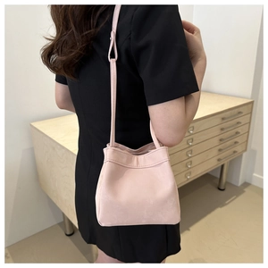 Detail of pink minimalist bucket bag showing soft matte texture and shoulder strap