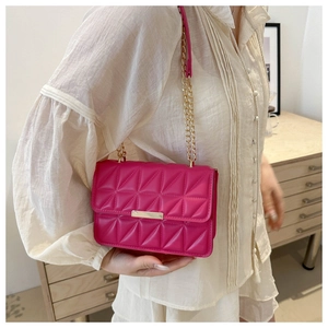 Close-up of rose red crossbody bag featuring triangle quilting and gold metal chain