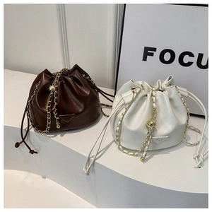 Close-up of drawstring bucket bags in brown and beige with golden chain straps