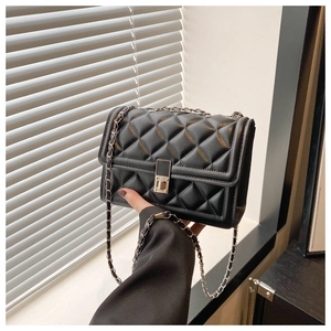 Détail du sac à bandoulière en cuir noir matelassé avec chaîne et fermoir en métal