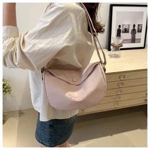 Detail of light pink moon bag featuring delicate butterfly embroidery on textured faux leather