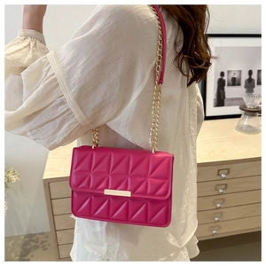 Detail of fuchsia quilted crossbody bag with gold hardware and elegant chain strap