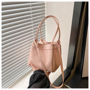 Detail shot of pale pink bucket bag showing soft suede texture and leather shoulder straps
