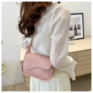 Détail du sac bandoulière rose clair avec rabat ondulé et bandoulière à nœuds