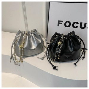 Detail of silver and black drawstring bucket bags with chain straps and gold sphere charms