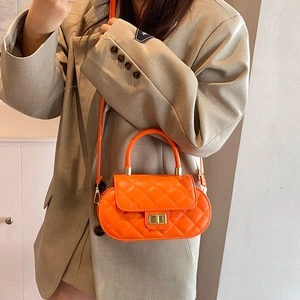 Chic orange quilted crossbody bag with gold lock and top handle shown on a model
