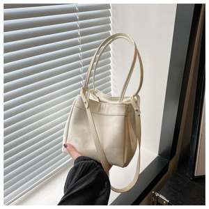 Detail shot of elegant cream leather bucket bag with silver metal rivet accents