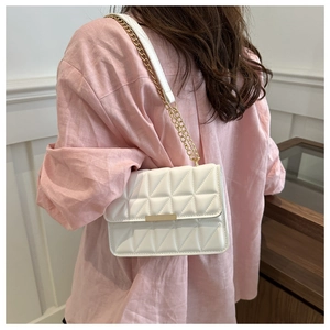 Detailed shot of white quilted crossbody bag with gold hardware and chain strap