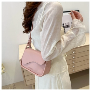 Sac bandoulière en cuir rose avec rabat festonné et logo JING PIN porté par un mannequin