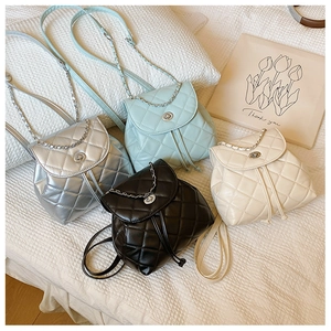Detailed display of mini quilted backpacks in silver, blue, black, and beige with chain straps