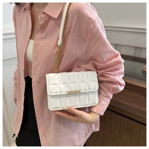 Close-up of a white quilted crossbody bag with gold hardware and elegant chain strap