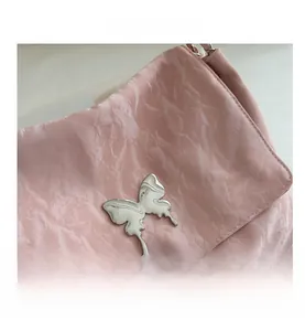 Close-up of pink pleated PU leather shoulder bag with a silver butterfly metal buckle