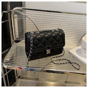 Détail du sac bandoulière en cuir matelassé noir avec chaîne argentée et fermoir pivotant