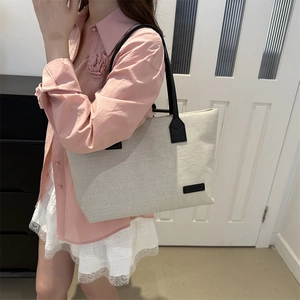 Minimalist off-white canvas tote bag with black straps for stylish daily commuting