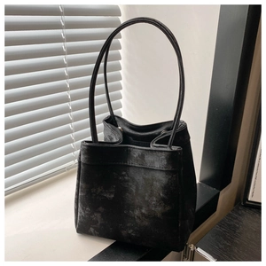 Detail of vintage textured black bucket bag with slim handles against window light