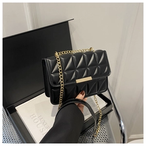 Detail of black quilted leather shoulder bag with gold chain strap and metal clasp