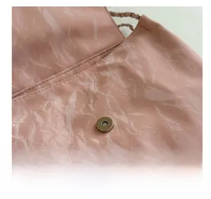 Close-up of pink textured PU leather bag with silver cylindrical magnetic closure detail