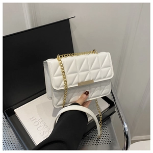 Detail of white quilted crossbody bag with gold chain strap and geometric patterns