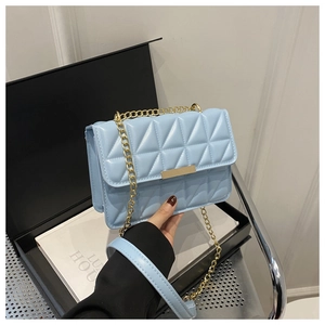 Detail of light blue quilted leather handbag with gold chain strap and metal clasp closure