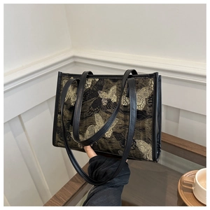 Detail of elegant black tote bag with gold butterfly embroidery and double leather straps
