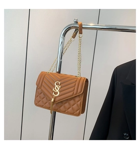Detail der braunen gesteppten Ledertasche mit goldenem Logo, Quaste und Kettenriemen