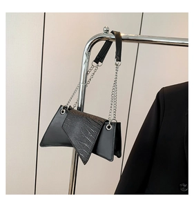 Detail of black asymmetrical handbag with sequined flap and silver chain strap