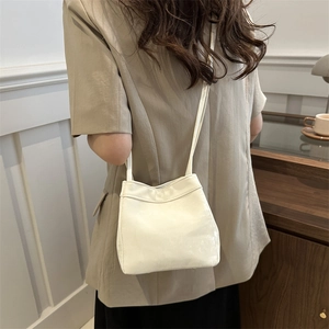 Minimalist cream white crossbody bucket bag styled with a professional blazer outfit