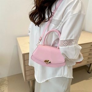 Sac bandoulière demi-lune rose avec fermoir en éventail porté par un mannequin chic