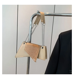 Detail of beige asymmetric bag featuring glossy faux crocodile flap and silver chain strap
