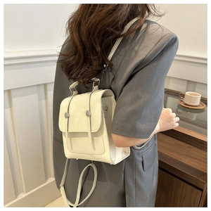 Vista laterale di uno zaino minimalista in ecopelle bianco crema indossato da una modella