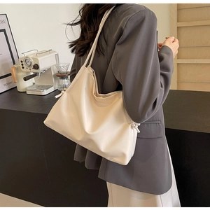 Dettaglio della borsa tote in pelle crema con eleganti nodi indossata da una modella