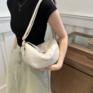 Minimalist beige dumpling shoulder bag with delicate butterfly embroidery in a warm interior
