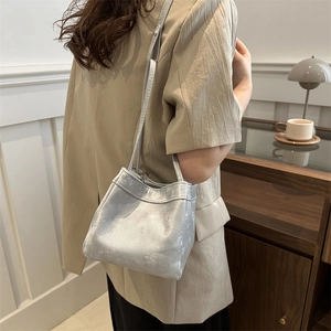 Silver metallic bucket bag with leather strap shown on model in cozy interior